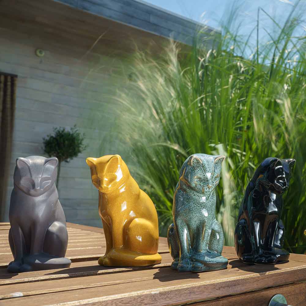 cat urns for ashes outside in sun on table