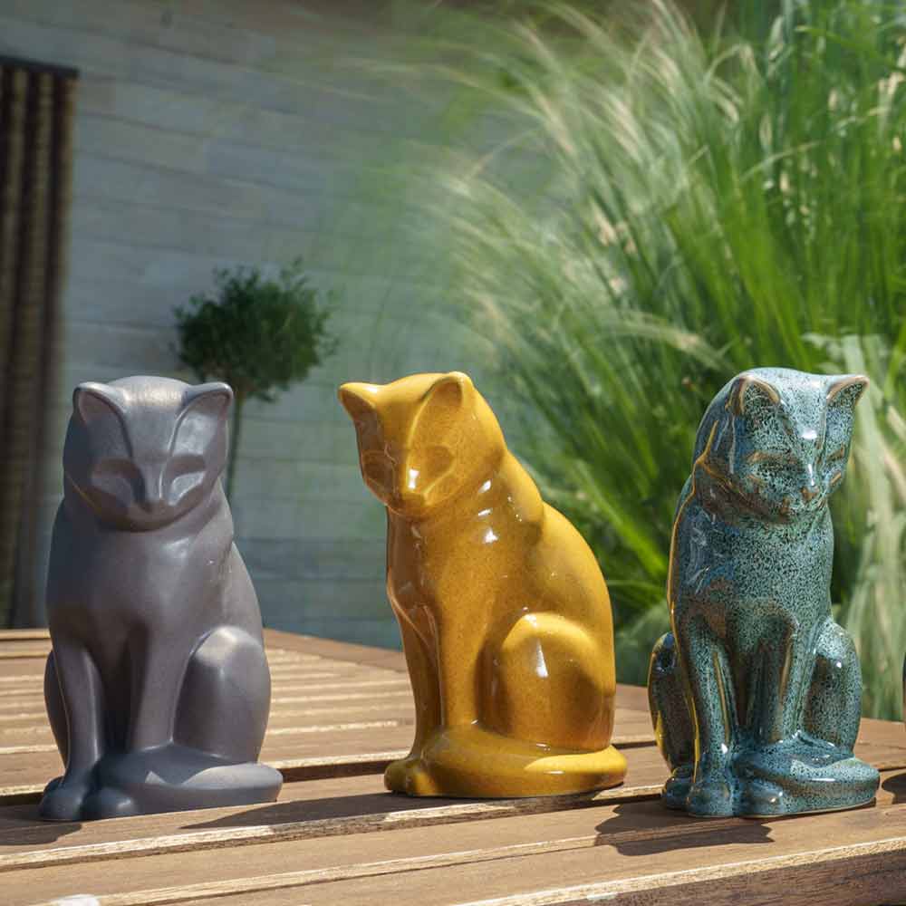 cat urns for ashes outside on table